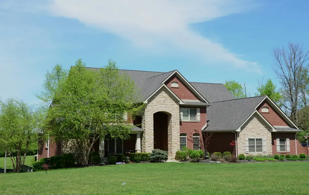 A large brick house with a thick green lawn in front